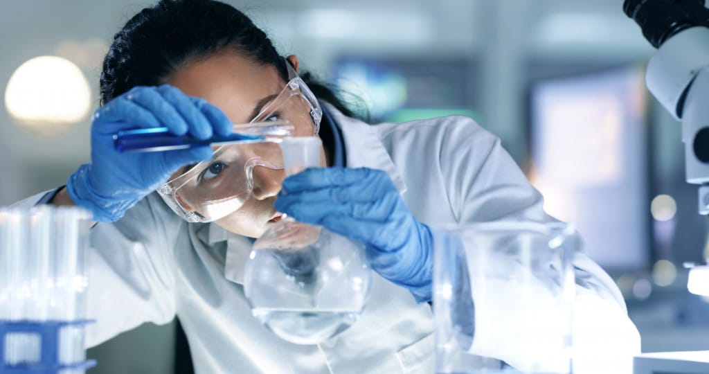 Thinking, focused and professional scientist doing research to create a cure in a research lab. Medical expert using science equipment in a laboratory. Serious female healthcare worker experimenting